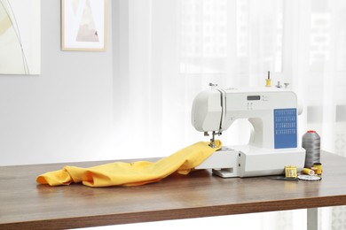 Photo of Sewing machine with fabric and craft accessories on wooden table indoors