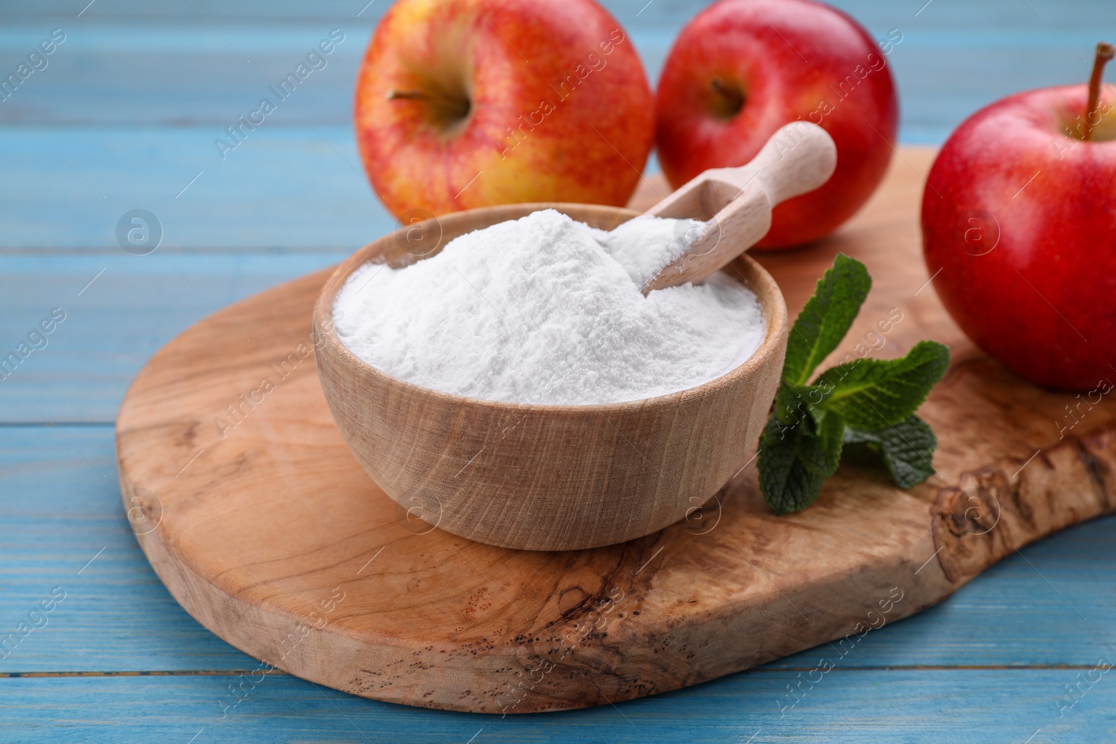 Photo of Sweet fructose powder, mint leaves and apples on light blue wooden table