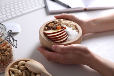 Woman with tasty granola at workplace, closeup