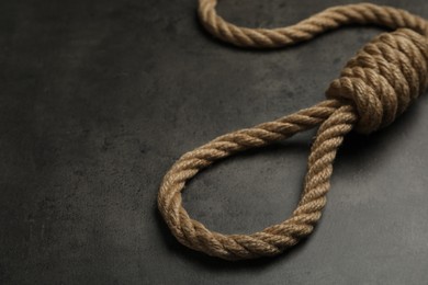 Photo of Rope noose with knot on grey table, closeup. Space for text