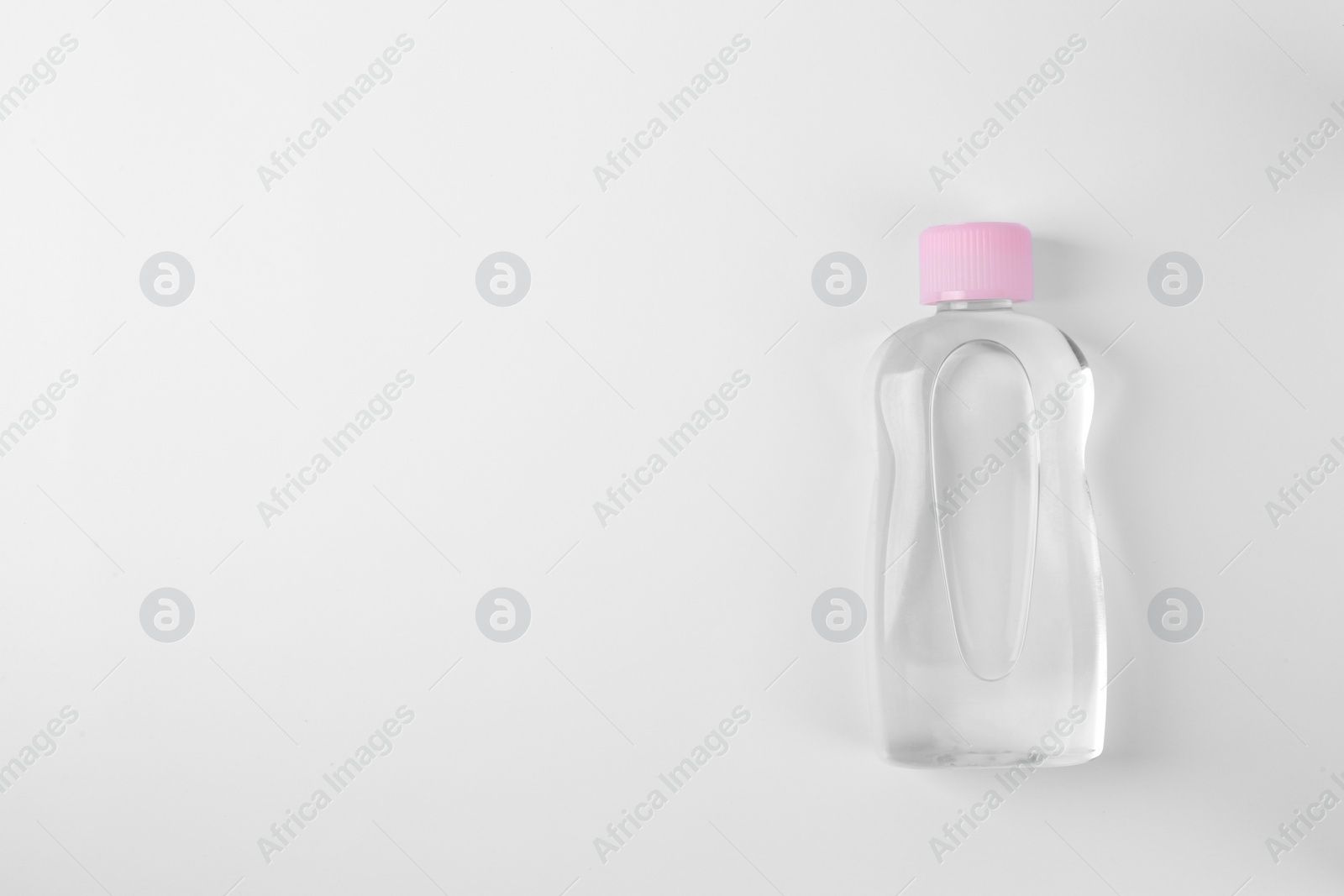 Photo of Transparent bottle with baby oil on white background, top view. Space for text