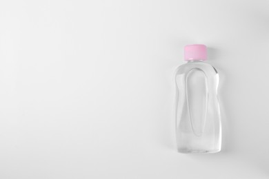 Photo of Transparent bottle with baby oil on white background, top view. Space for text