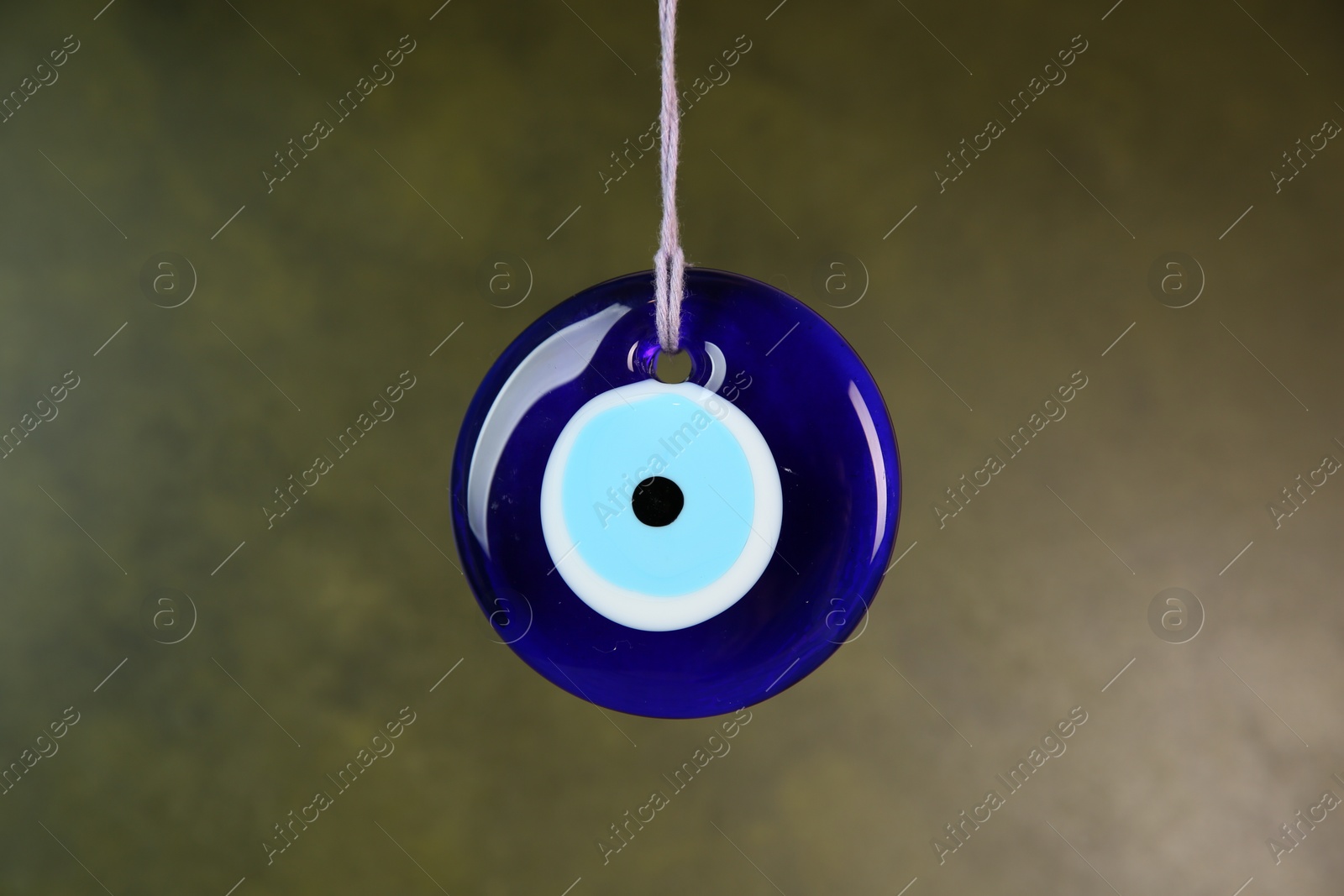 Photo of Evil eye amulet hanging on olive background, closeup