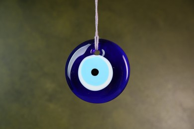 Photo of Evil eye amulet hanging on olive background, closeup