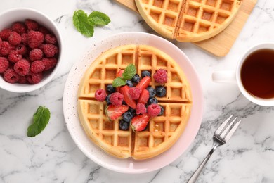 Tasty Belgian waffles with fresh berries served on white marble table, flat lay