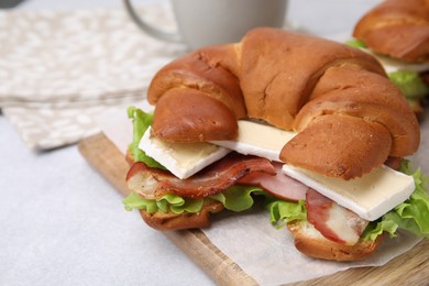 Photo of Tasty crescent roll with brie cheese, ham and bacon on white table, closeup