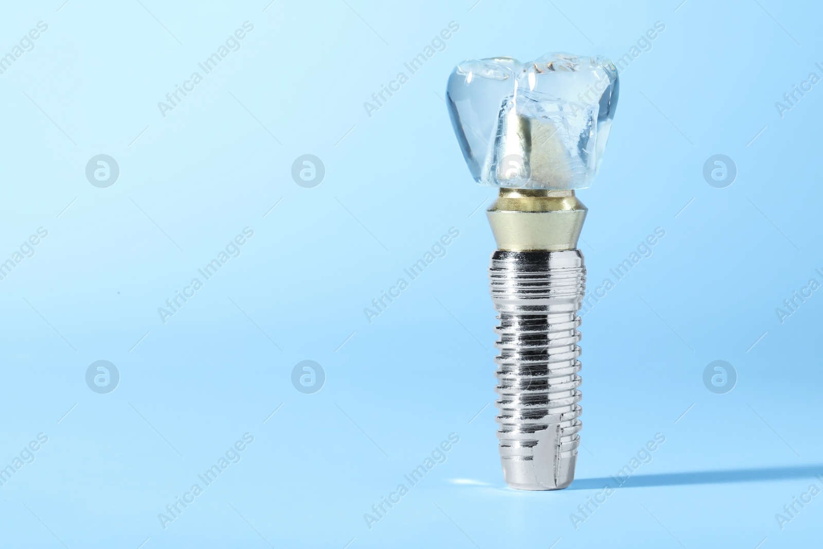 Photo of Educational model of dental implant on light blue background. Space for text