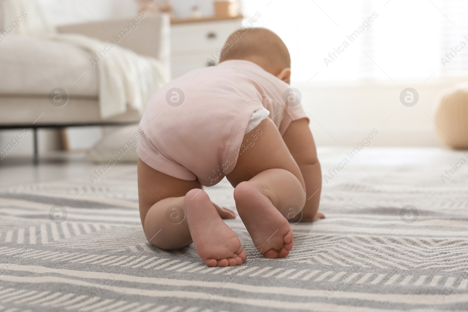 Photo of Cute baby crawling at home, focus on legs