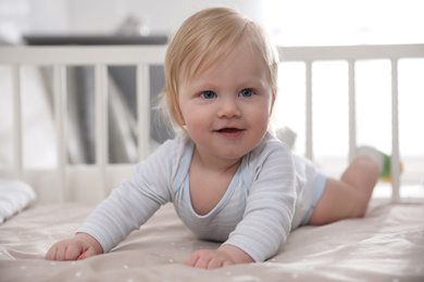 Photo of Adorable little baby lying in comfortable crib