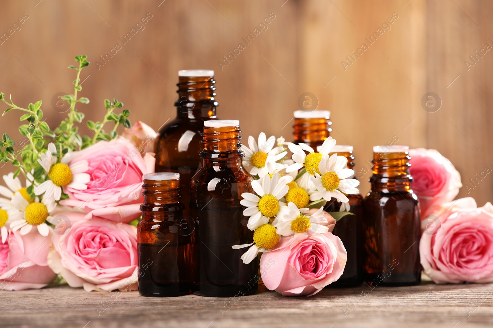 Photo of Bottles with essential oils, thyme and flowers on wooden table, closeup