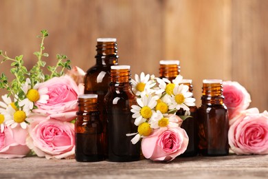 Bottles with essential oils, thyme and flowers on wooden table, closeup