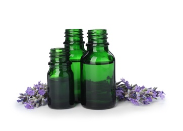 Photo of Bottles with natural lavender oil and flowers on white background