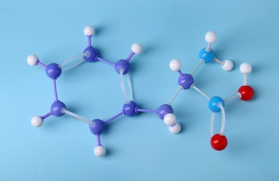 Molecule of phenylalanine on light blue background, top view. Chemical model