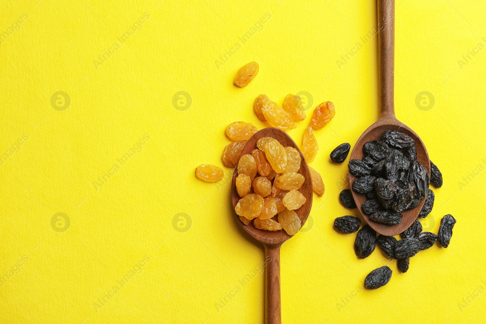 Photo of Spoons with raisins and space for text on color background, top view. Dried fruit as healthy snack