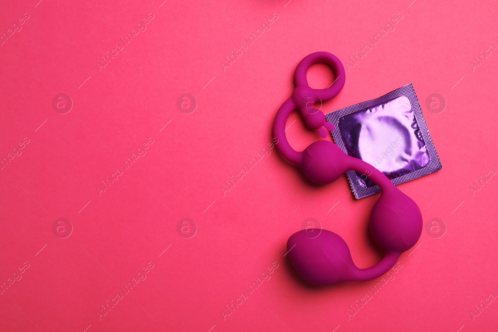 Photo of Anal balls and condom on pink background, top view with space for text. Sex game