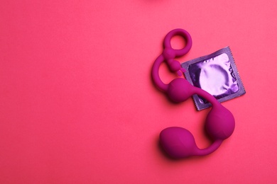 Photo of Anal balls and condom on pink background, top view with space for text. Sex game