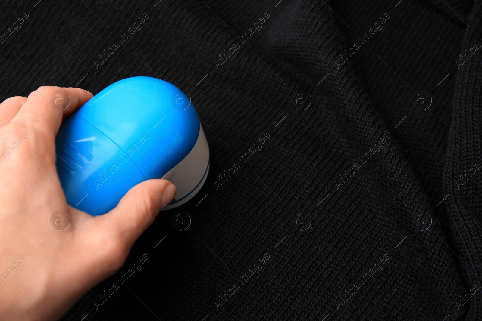 Photo of Woman using fabric shaver on black cloth with lint, closeup. Space for text