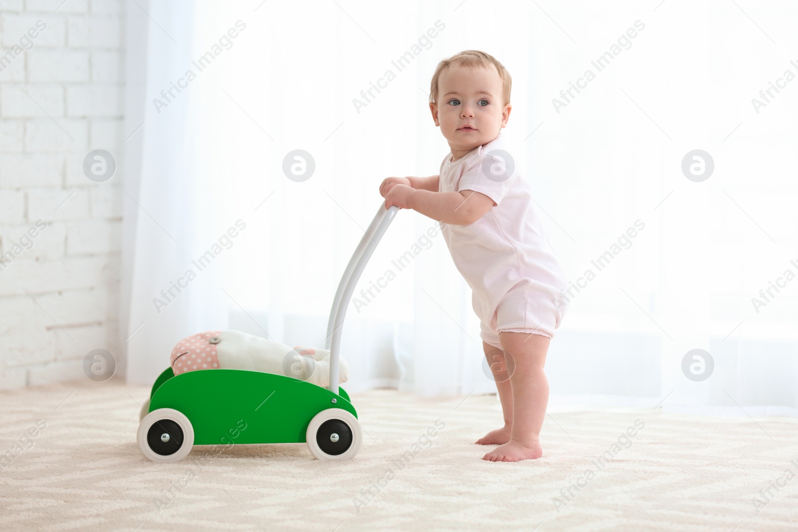 Photo of Cute baby with toy walker indoors