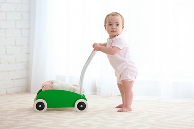 Photo of Cute baby with toy walker indoors