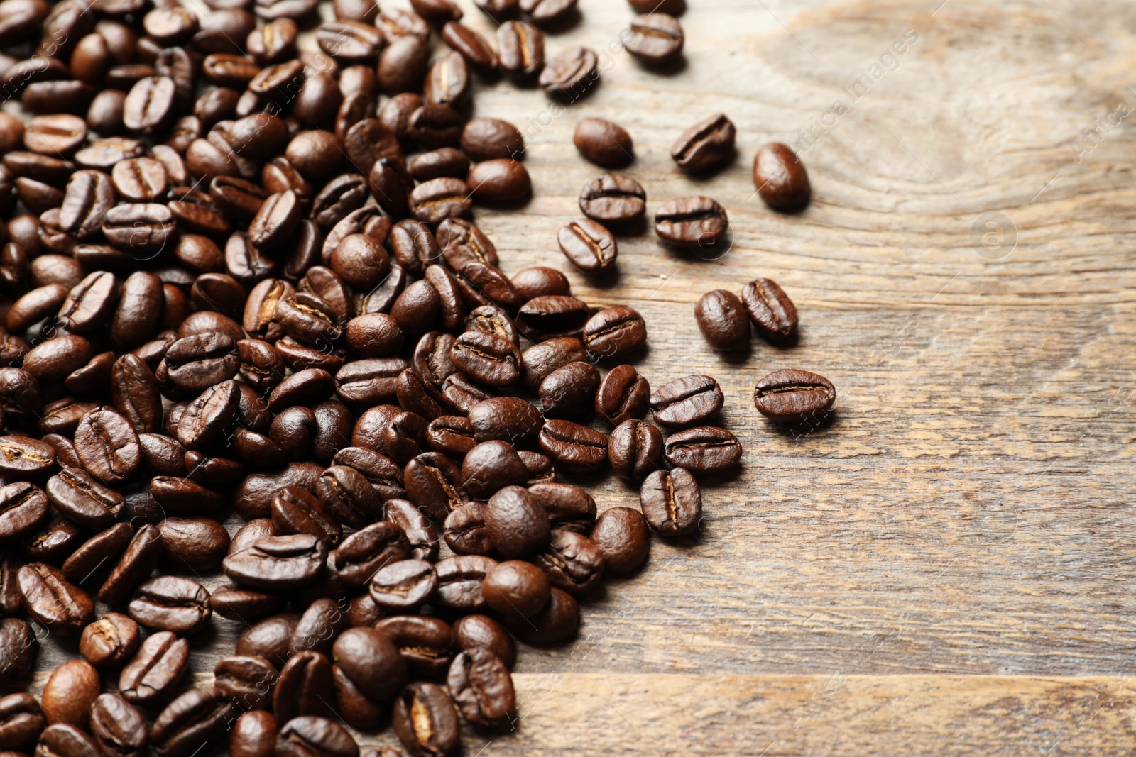 Photo of Pile of roasted coffee beans on wooden background