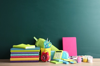 Photo of Different school stationery on table near blank chalkboard. Space for text