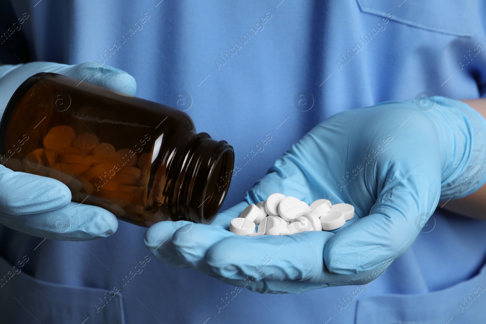 Photo of Doctor pouring pills from bottle onto hand, closeup view