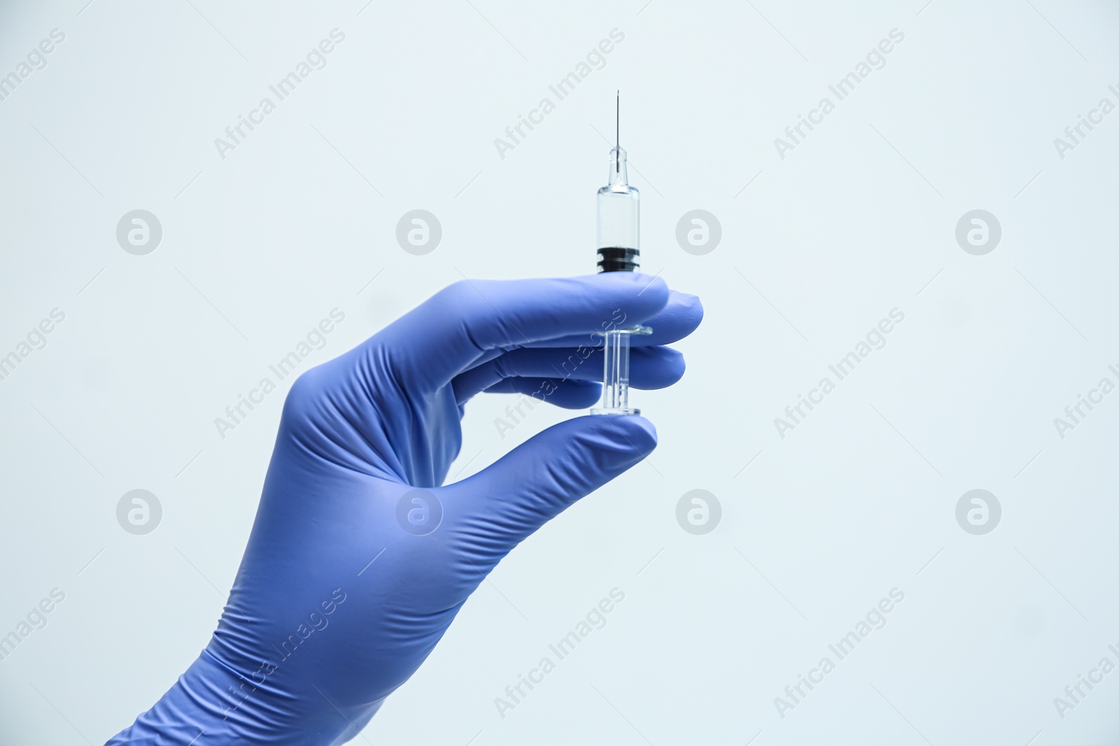 Photo of Doctor holding syringe with COVID-19 vaccine on light background, closeup