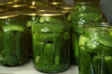 Photo of Glass jars with pickled cucumbers on table