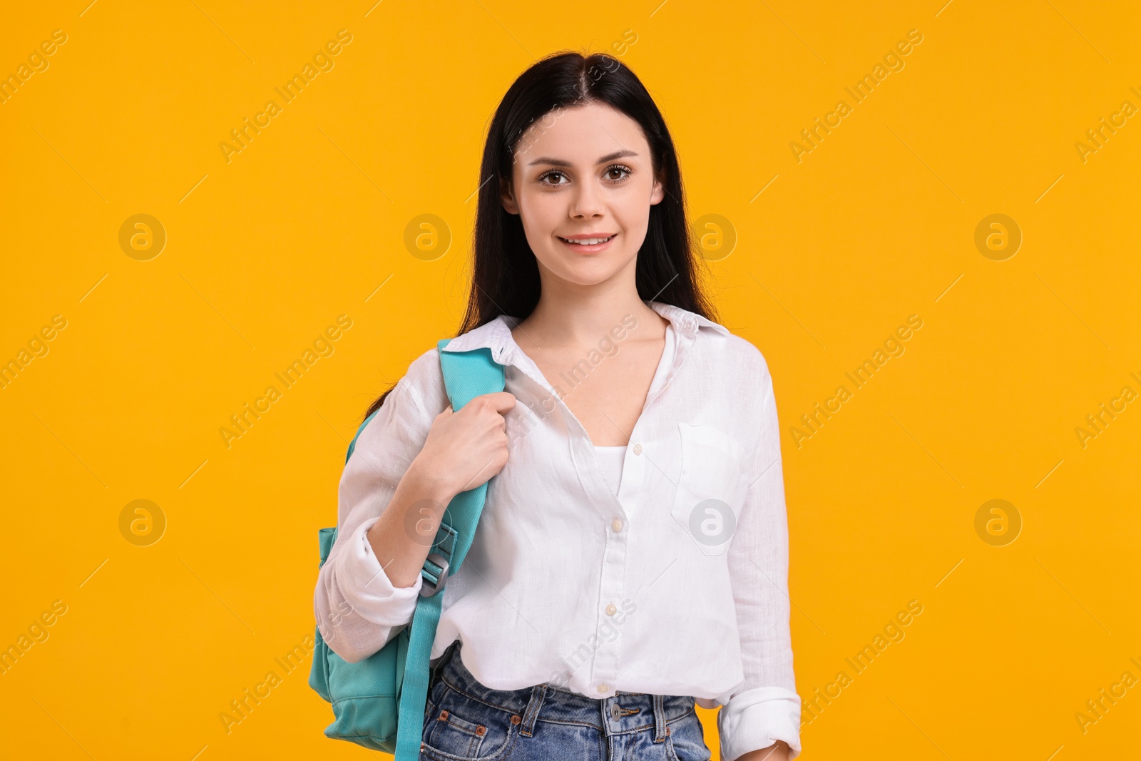 Photo of Smiling student with backpack on yellow background