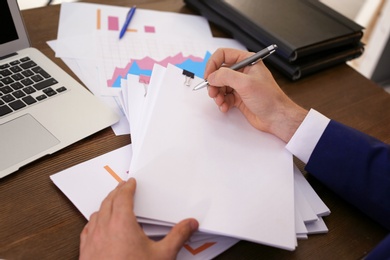 Photo of Businessman working with documents at office table, closeup. Space for text
