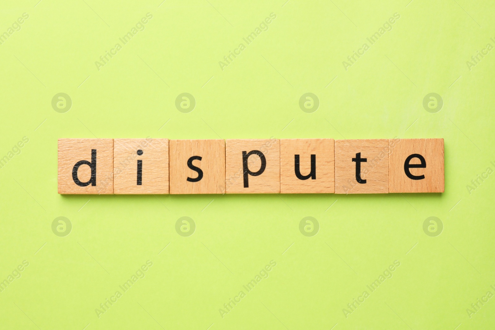 Photo of Word Dispute made with wooden cubes on light green background, top view