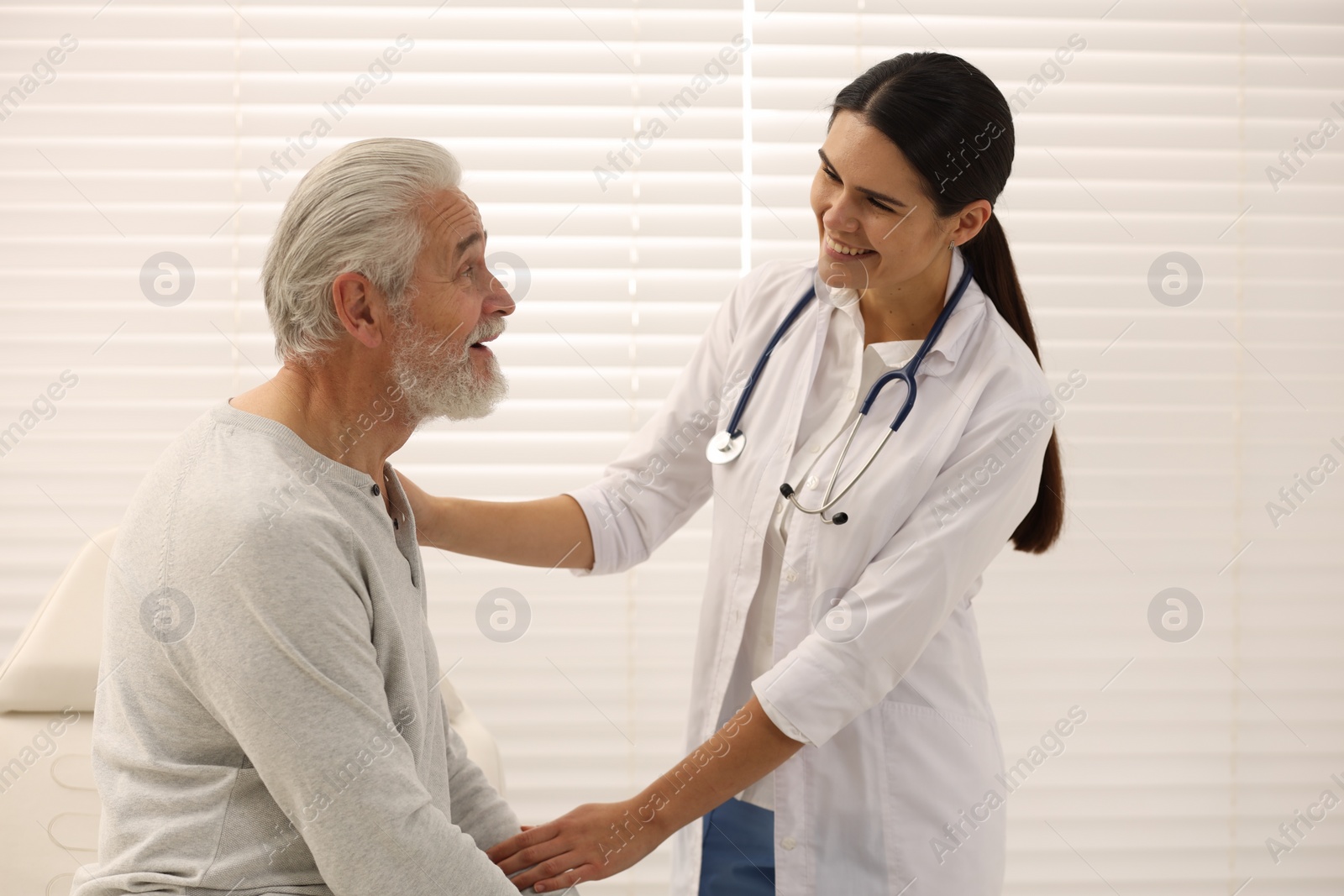 Photo of Smiling nurse supporting elderly patient in hospital