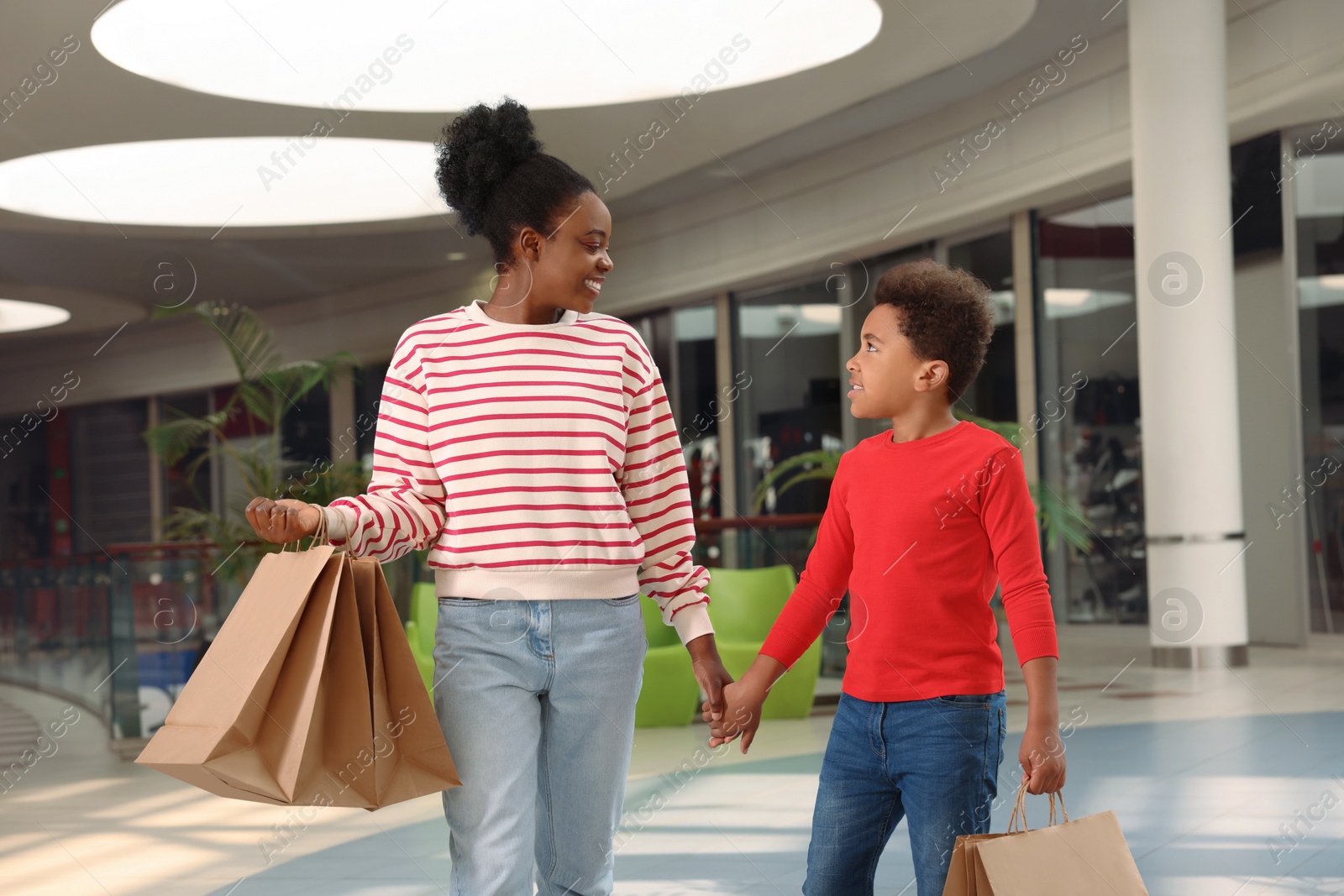 Photo of Family shopping. Happy mother and son with purchases in mall