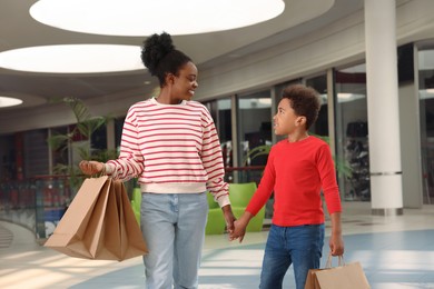 Photo of Family shopping. Happy mother and son with purchases in mall
