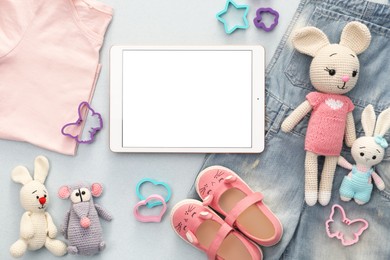 Photo of Modern tablet, clothes and toys on light grey background, flat lay. Space for text