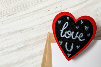 Heart with words I Love You and envelopes on white wooden background, flat lay. Space for text