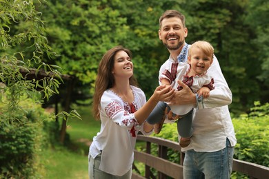 Photo of Happy family in Ukrainian national clothes outdoors