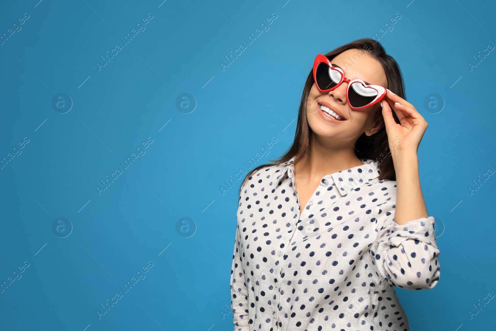 Photo of Portrait of beautiful young woman with heart shaped sunglasses on color background. Space for text