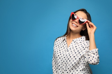 Photo of Portrait of beautiful young woman with heart shaped sunglasses on color background. Space for text