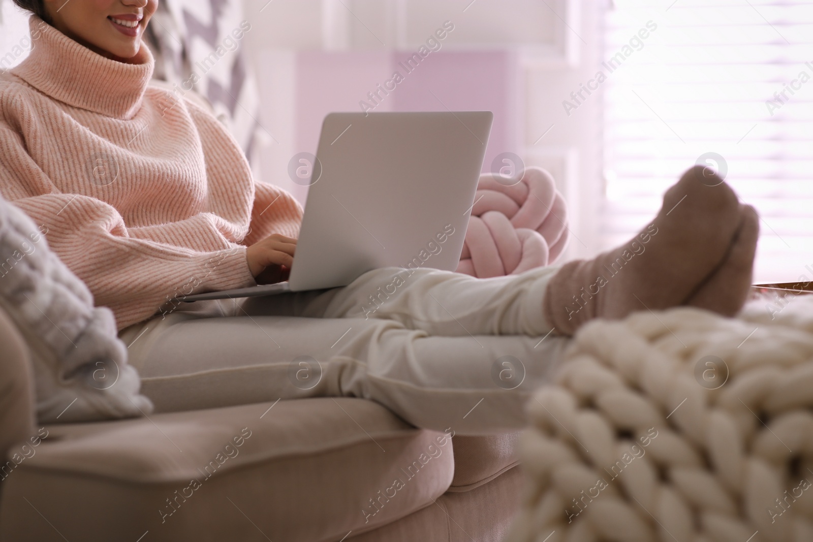 Photo of Woman with laptop relaxing at home, closeup. Cozy atmosphere