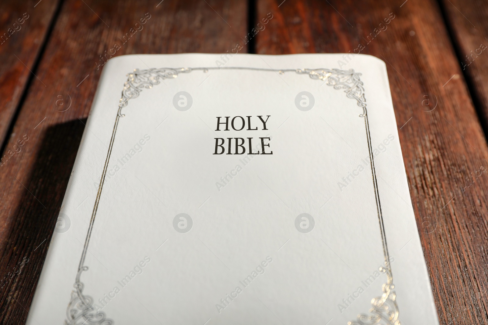 Photo of Old hardcover Bible on wooden table, closeup. Religious book