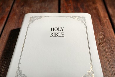 Old hardcover Bible on wooden table, closeup. Religious book
