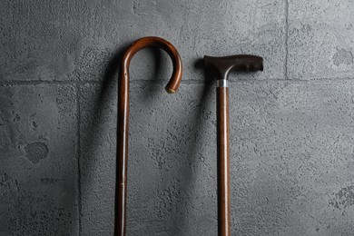 Different walking canes on grey stone background, closeup
