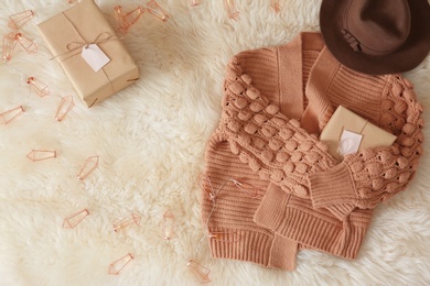 Flat lay composition with warm sweater and gift boxes on fuzzy carpet