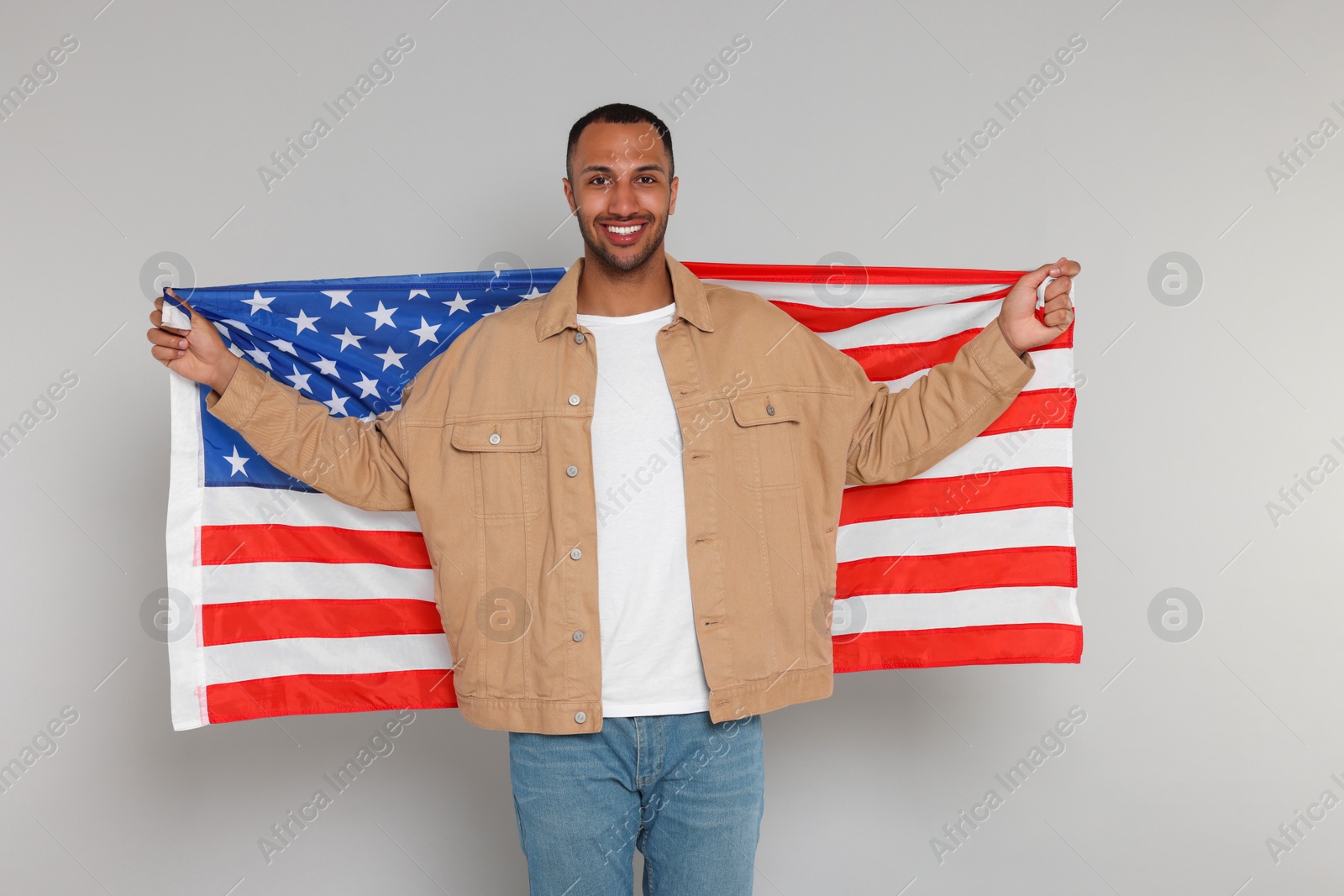 Photo of 4th of July - Independence Day of USA. Happy man with American flag on light grey background