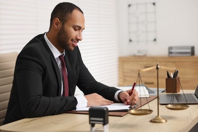 Photo of Smiling lawyer working at table in office