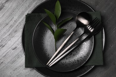 Elegant table setting. Plates, cutlery, napkin and branch with green leaves, flat lay