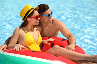 Happy couple with inflatable ring in swimming pool. Summer vacation