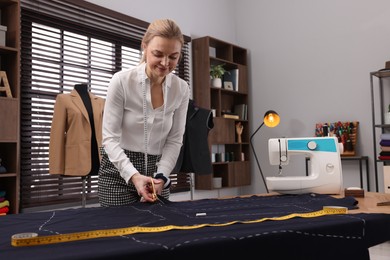 Photo of Dressmaker cutting fabric by following chalked sewing pattern in workshop