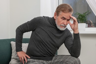 Photo of Upset senior man on sofa at home. Loneliness concept